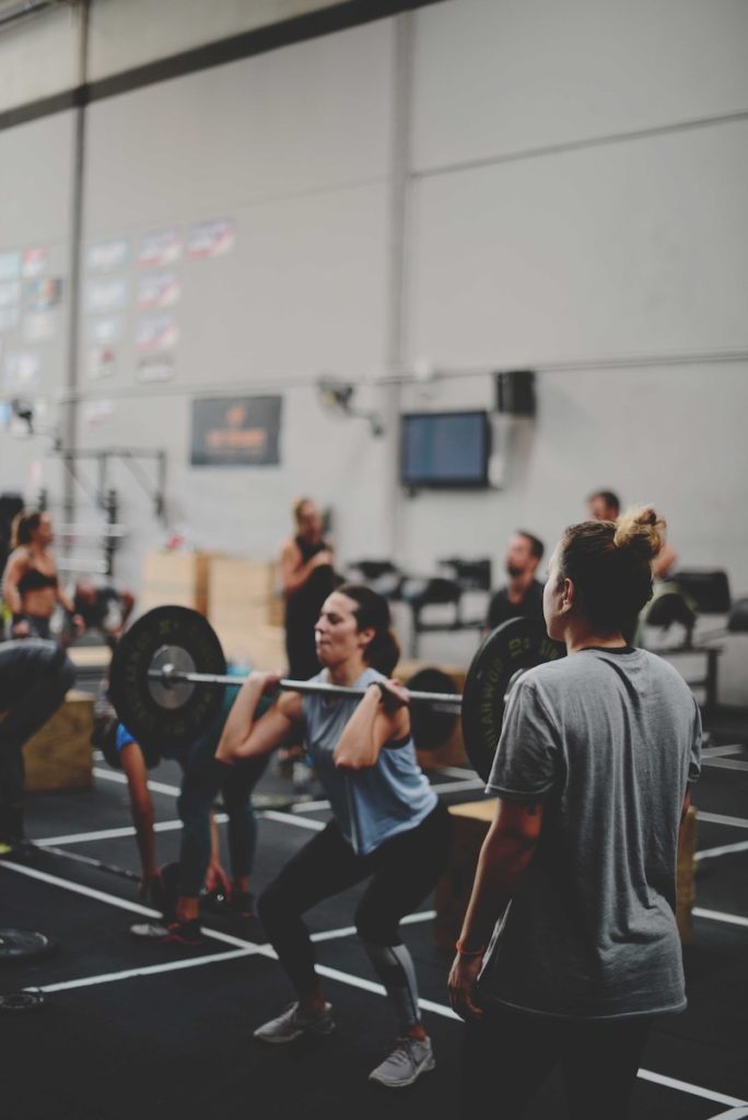 A woman lifting weights in a busy gym