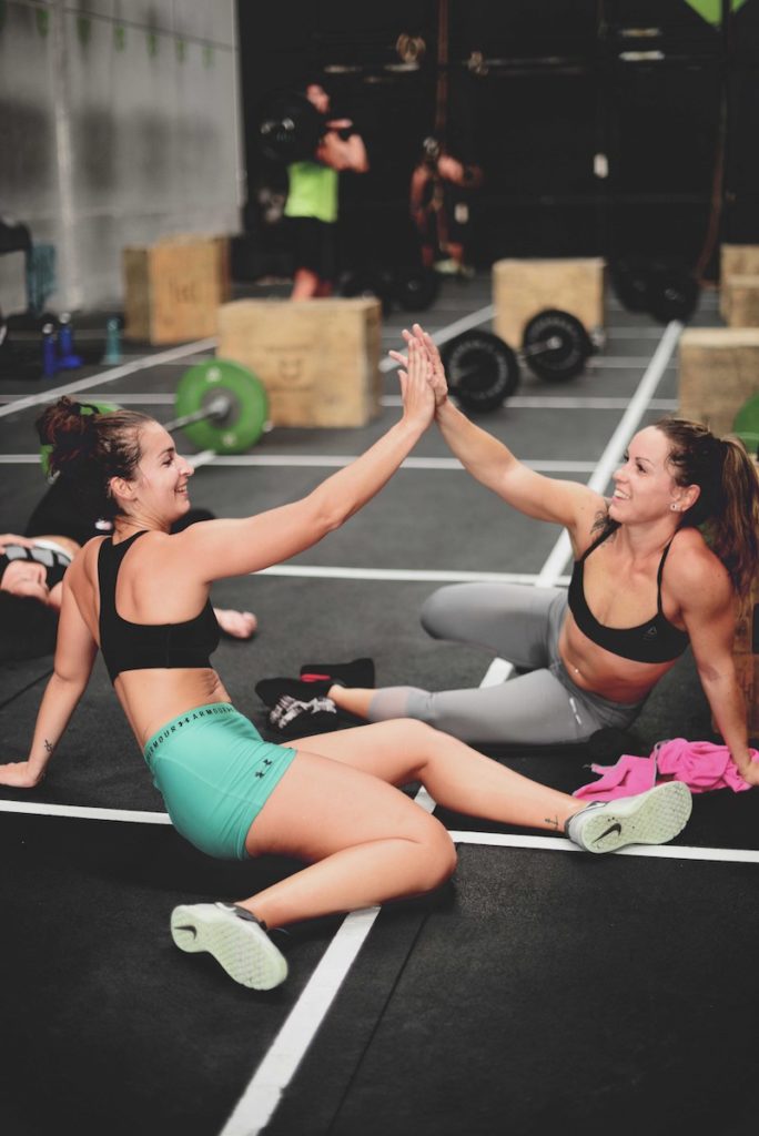 Women high-fiving on the ground at the gym