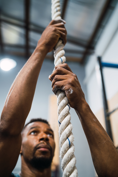 Man rope climbing at CrossFit gym