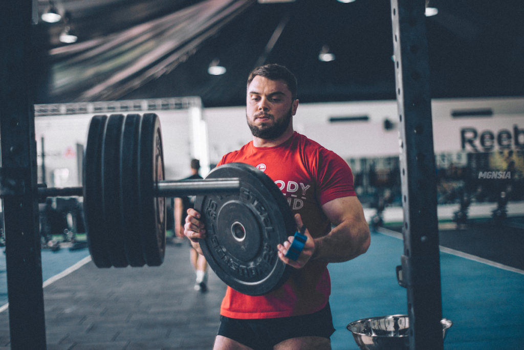 Oleksiy Torokhtiy loading plates on a barbell